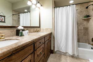 Bathroom featuring double vanity, shower / tub combo, tile patterned floors, backsplash, and recessed lighting