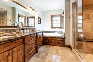 Full bath with plenty of natural light, double vanity, a bath, and a tile shower