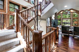 Stairs with wood finished floors, high vaulted ceiling, and recessed lighting