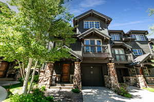 Craftsman-style house featuring a balcony, stone siding, driveway, and an attached garage