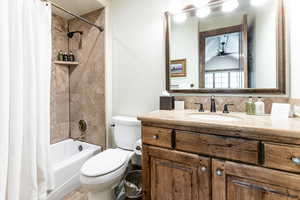 Full bath featuring vanity, shower / tub combo with curtain, and ceiling fan