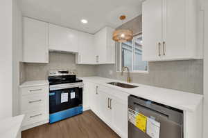 Kitchen featuring stainless steel electric range oven, dishwashing machine, white cabinets, dark wood-style floors, and light countertops