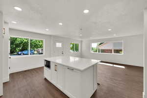 Kitchen featuring recessed lighting, white cabinetry, a center island, dark wood-type flooring, and light countertops