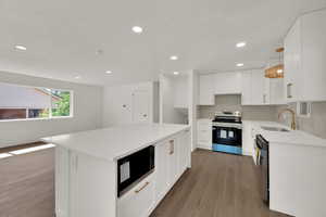 Kitchen with appliances with stainless steel finishes, wood finished floors, light countertops, white cabinetry, and recessed lighting