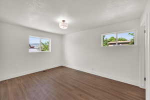 Unfurnished room with plenty of natural light and dark wood-type flooring