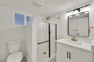 Full bathroom with vanity, tiled shower, and a textured ceiling