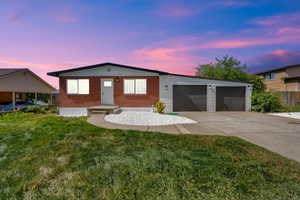 Ranch-style house with concrete driveway, a front yard, an attached garage, and brick siding