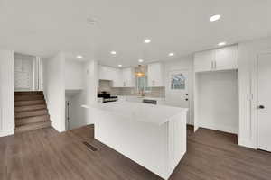 Kitchen with stainless steel range with electric stovetop, white cabinets, recessed lighting, a kitchen island, and light countertops