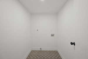 Laundry area with electric dryer hookup, hookup for a washing machine, and dark flooring