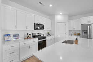 Kitchen featuring stainless steel appliances, light countertops, recessed lighting, and white cabinetry