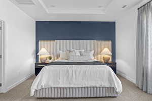 Bedroom with a tray ceiling and carpet floors