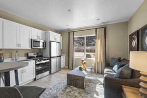 Kitchen with appliances with stainless steel finishes, light wood finished floors, and white cabinetry