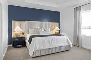 Bedroom with carpet floors and a tray ceiling