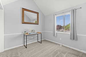 Carpeted office with vaulted ceiling and baseboards