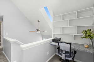 Unfurnished office with carpet, a ceiling fan, and built in desk