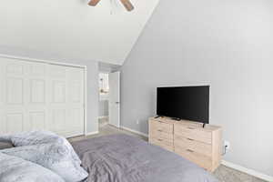 Bedroom featuring carpet, ceiling fan, lofted ceiling, and a closet