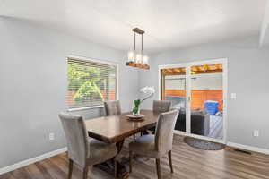 Dining area with wood finished floors and a chandelier