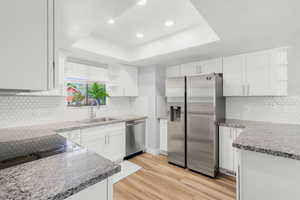 Kitchen featuring appliances with stainless steel finishes, open shelves, a raised ceiling, white cabinetry, and recessed lighting