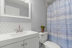 Full bathroom with tasteful backsplash, vanity, a shower with shower curtain, and a textured ceiling