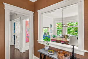 Hallway with crown molding, wood finished floors, and a chandelier