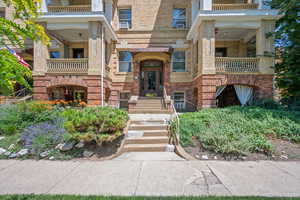 View of exterior entry with brick siding, a balcony, and cooling unit