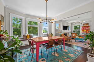 Dining area with a glass covered fireplace, dark wood-type flooring, crown molding, and a chandelier