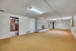 Unfurnished living room featuring carpet, a fireplace, and a textured ceiling