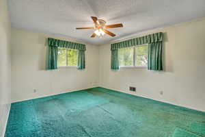 Carpeted spare room featuring ceiling fan and a textured ceiling