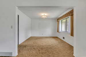 Unfurnished room with a textured ceiling and carpet floors