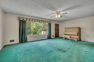 Unfurnished living room with ceiling fan, carpet flooring, and a textured ceiling