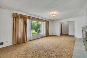 Unfurnished living room featuring carpet and a textured ceiling
