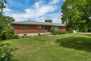 Single story home featuring brick siding, a front lawn, and a chimney