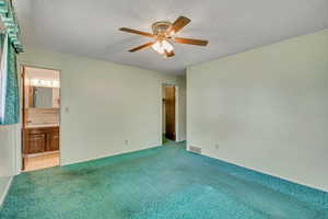 Unfurnished bedroom featuring carpet floors, a textured ceiling, connected bathroom, and a ceiling fan
