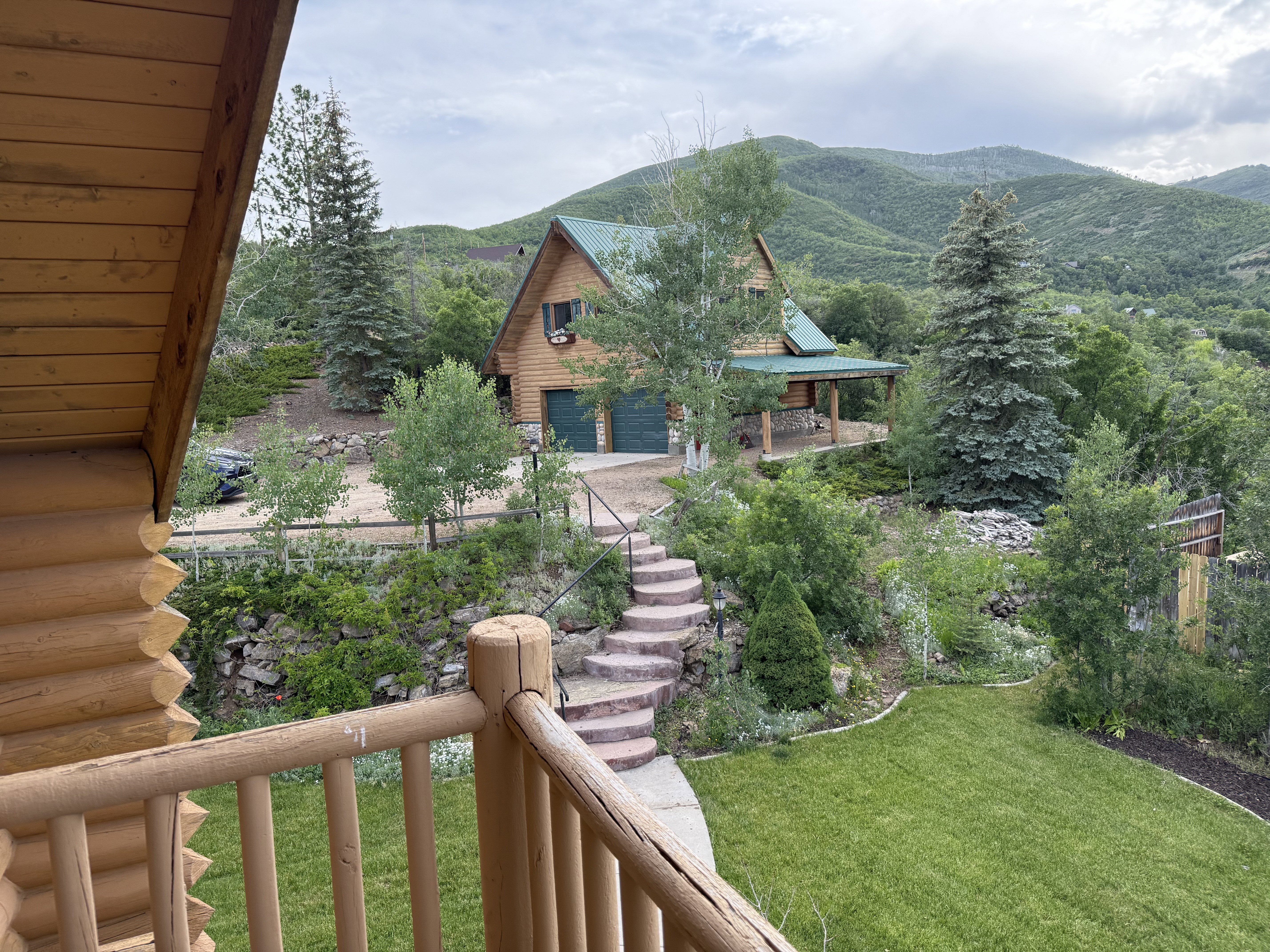 View of green lawn with a mountain view, a detached garage, and stairs