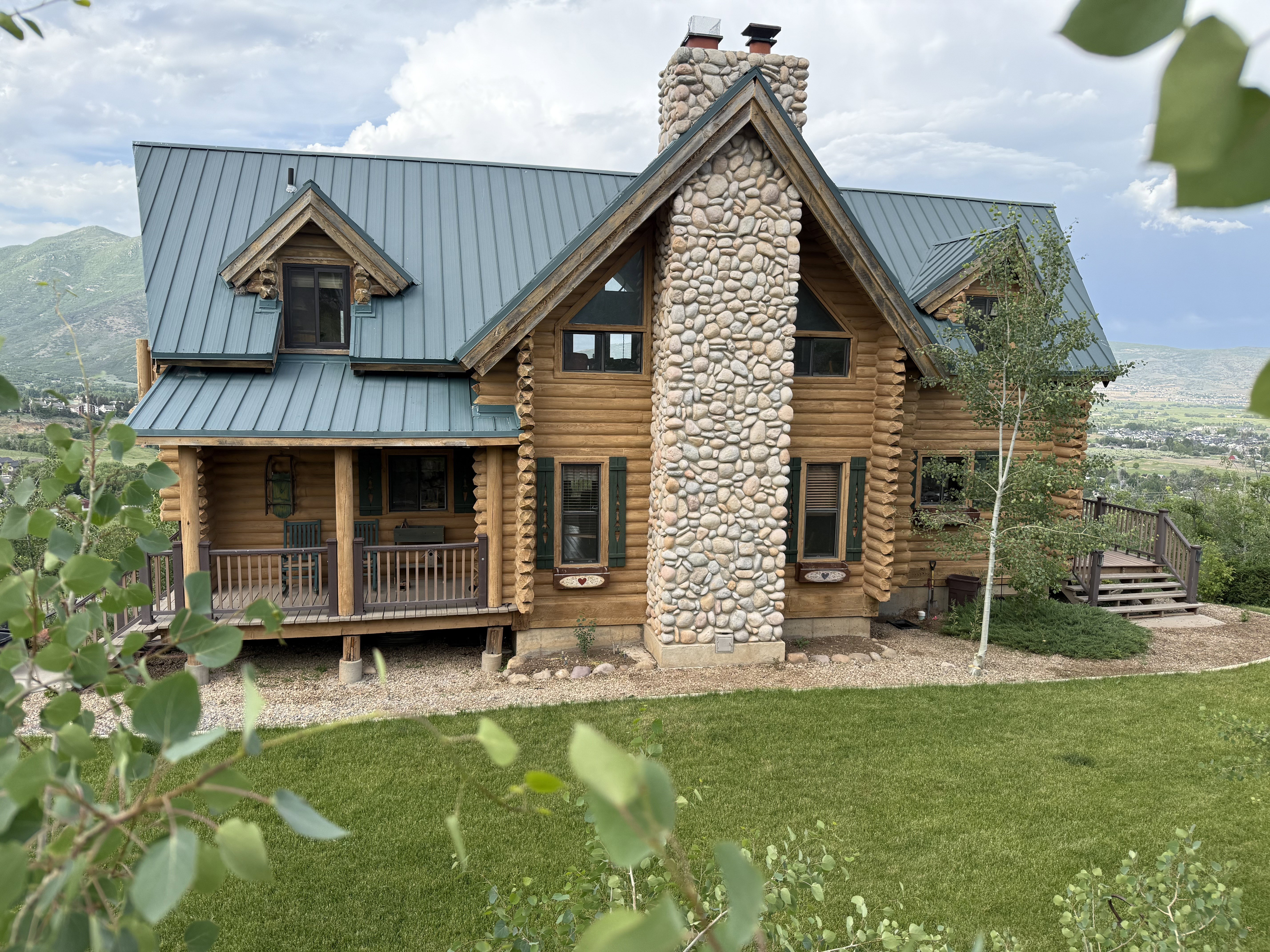 Back of house featuring a standing seam roof, a chimney, log exterior, a metal roof, and a mountain view