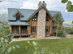 Back of house featuring a standing seam roof, a chimney, log exterior, a metal roof, and a mountain view