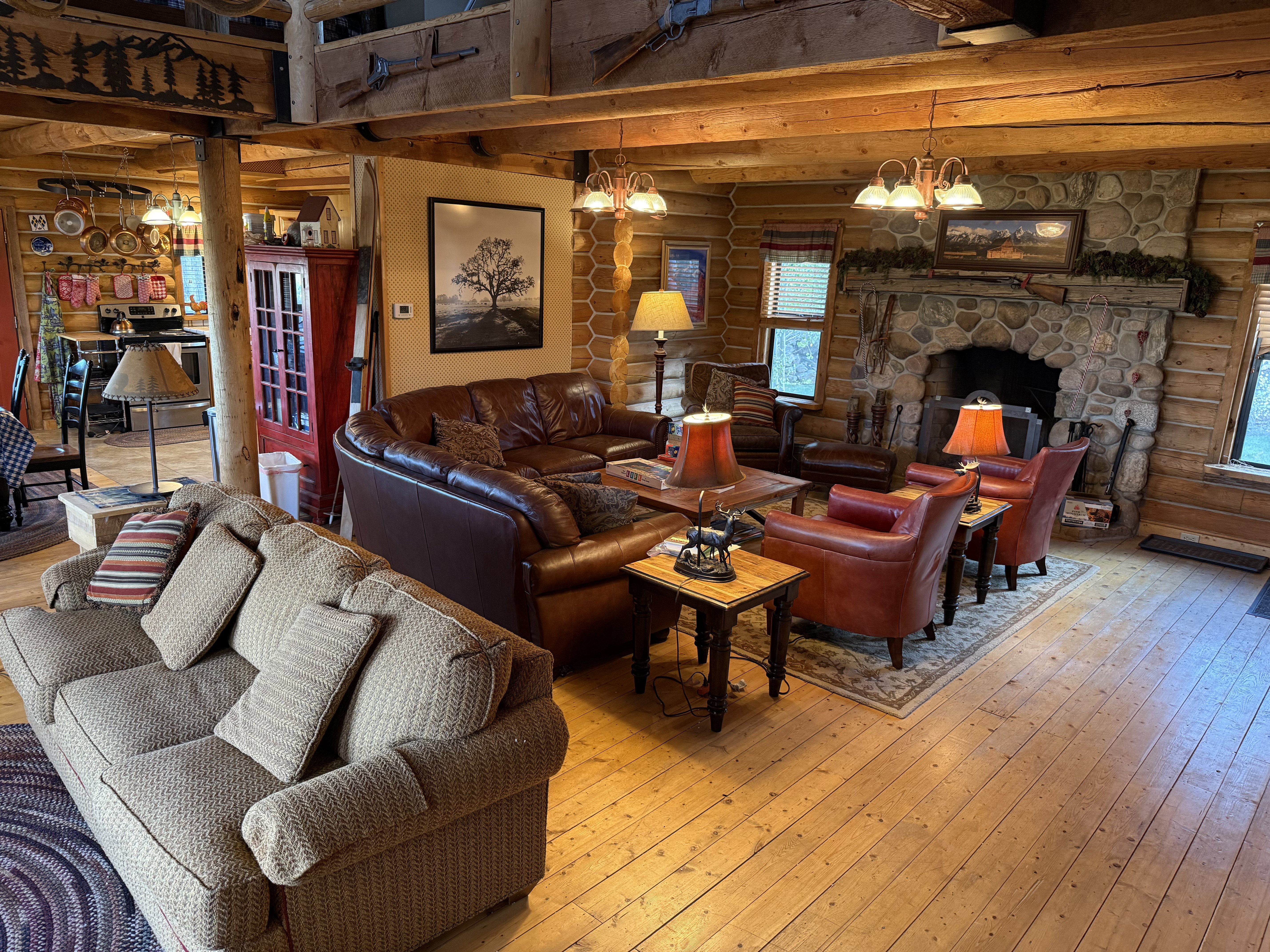 Living room with rustic walls, a chandelier, hardwood / wood-style flooring, healthy amount of natural light, and a fireplace