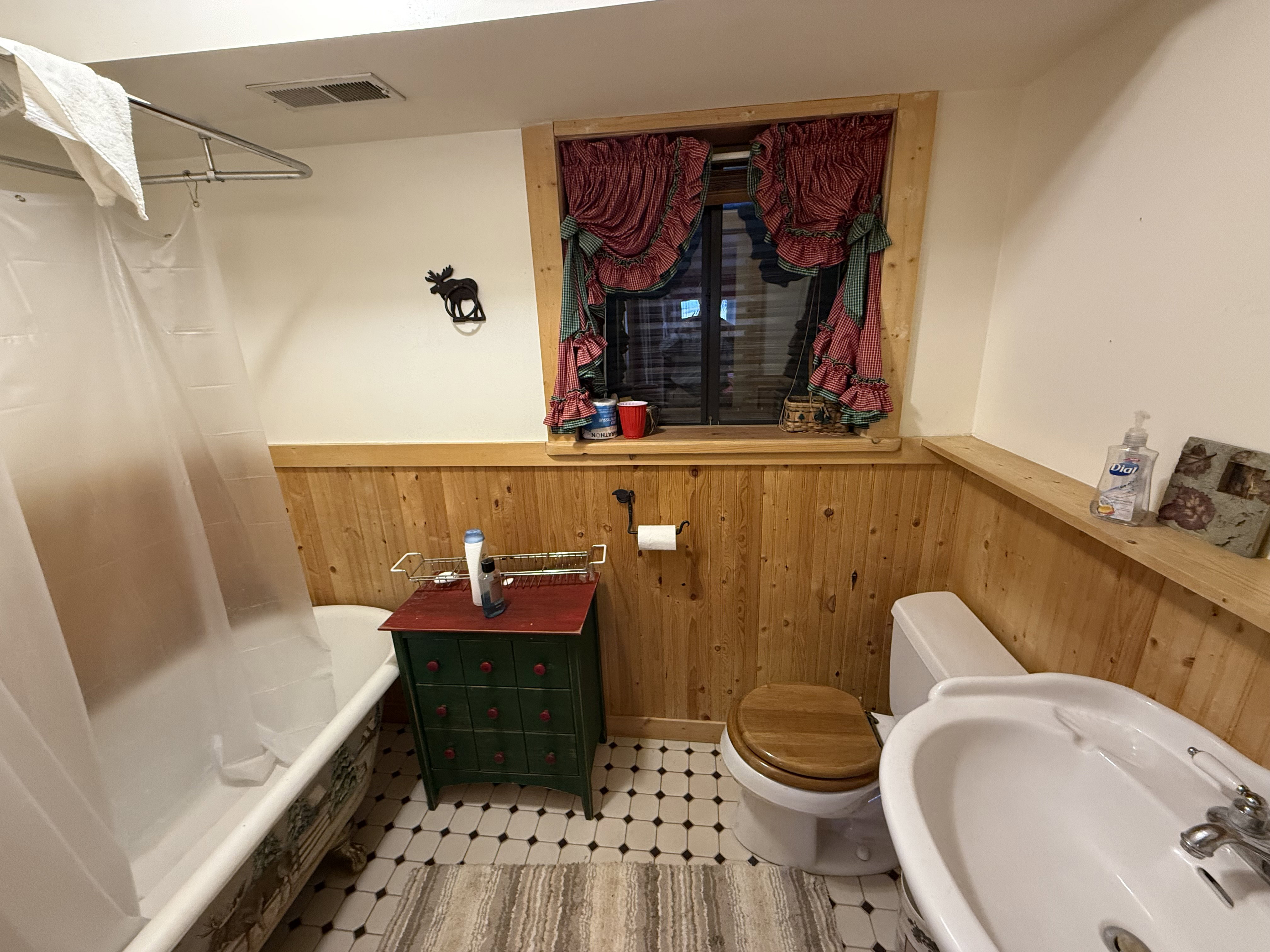 Bathroom featuring a wainscoted wall, wood walls, tile patterned floors, and shower / bathtub combination with curtain