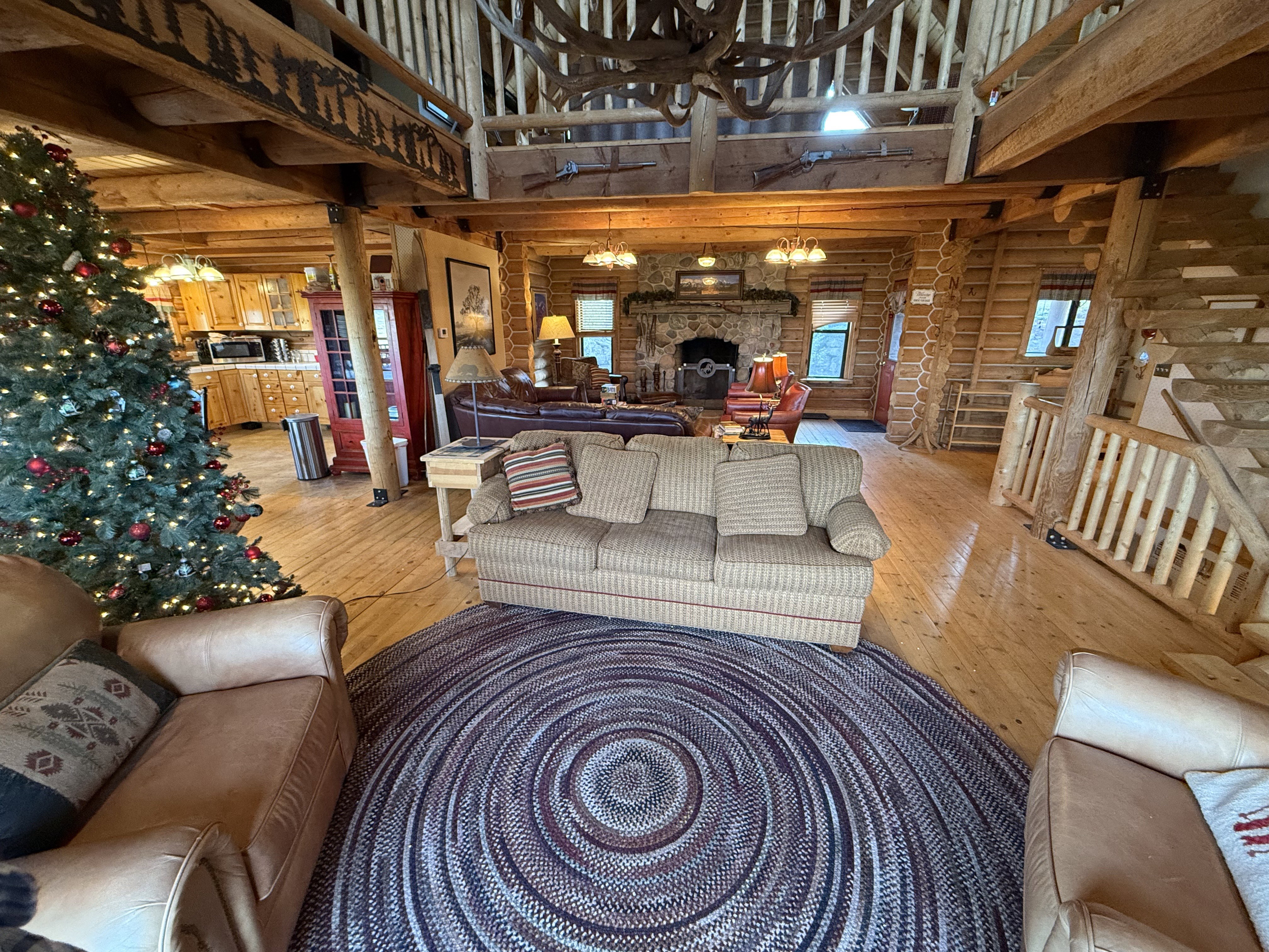 Living area with log walls, light wood-type flooring, and a high ceiling