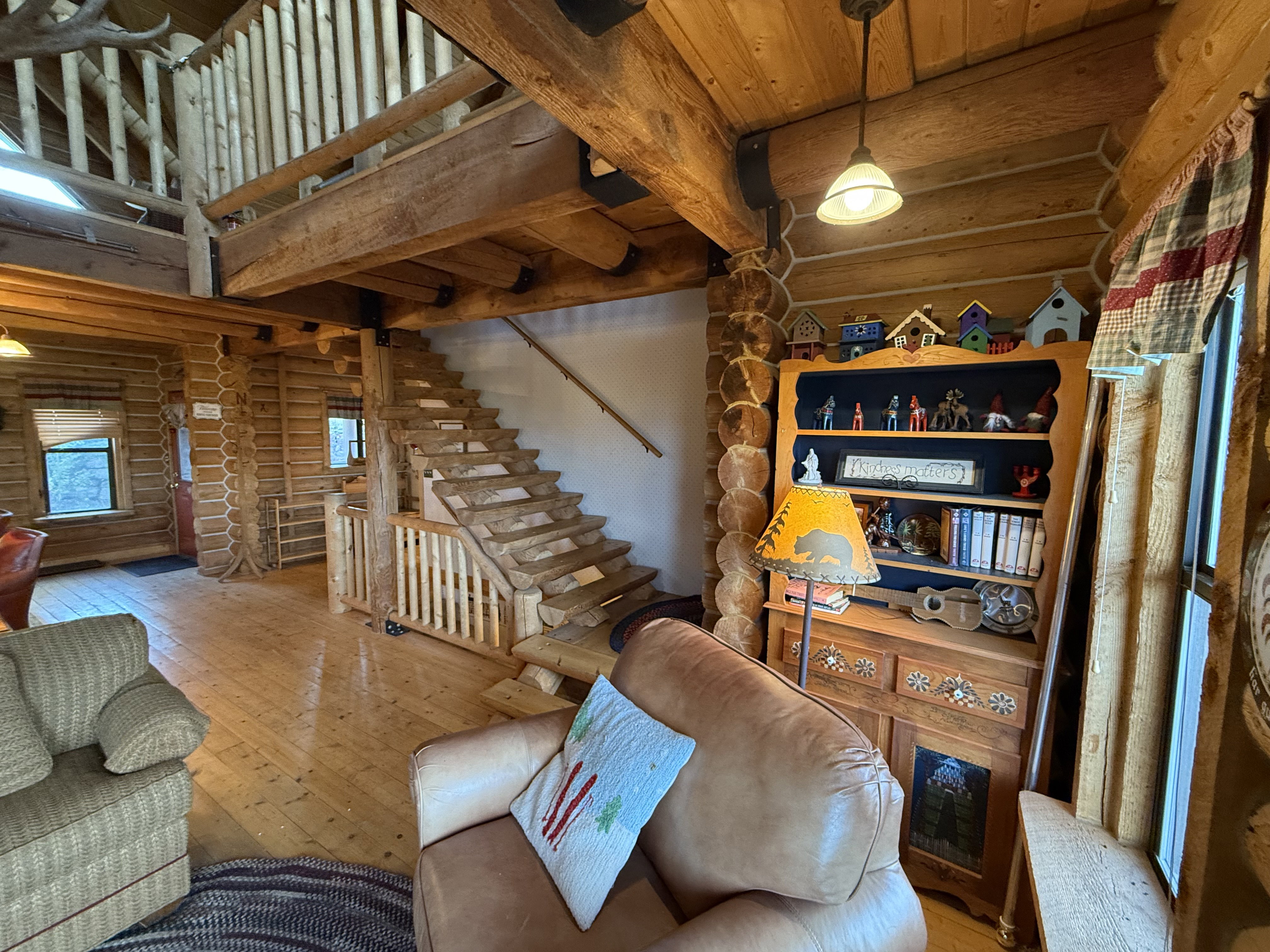 Living area with log walls, hardwood / wood-style floors, a wood ceiling with exposed beams, and stairway