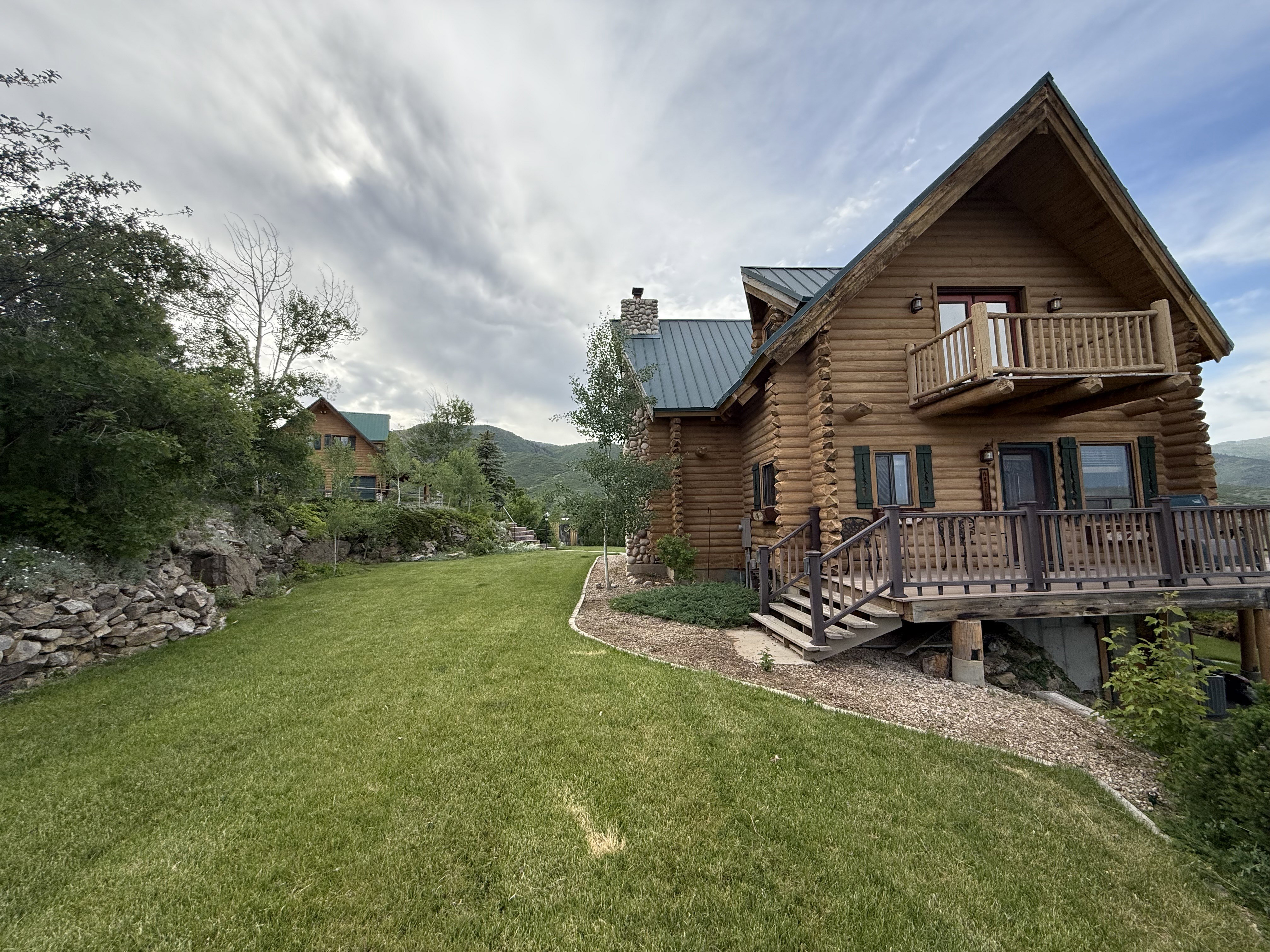 View of grassy yard featuring a balcony and a deck with mountain view