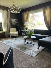 Living area with carpet floors, a chandelier, and wood walls, large picture window with mountain views.