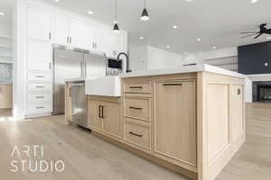 Kitchen with light brown cabinetry, recessed lighting, light wood-style flooring, a fireplace, and built in appliances
