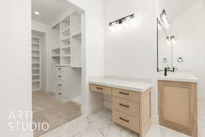 Full bathroom featuring vanity, a walk in closet, light marble finish floors, and recessed lighting