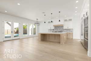 Kitchen featuring light brown cabinetry, backsplash, glass insert cabinets, french doors, and light wood-style floors