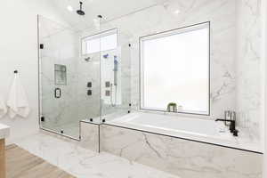 Bathroom with a marble finish shower, a bath, and vaulted ceiling