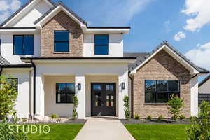 View of front of property featuring stucco siding, a front lawn, stone siding, and french doors