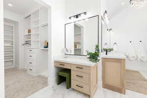 Full bath featuring a spacious closet, vanity, recessed lighting, light carpet, and light marble finish flooring