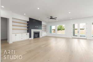 Unfurnished living room featuring a premium fireplace, recessed lighting, light wood-style floors, built in shelves, and ceiling fan