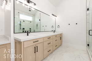 Bathroom featuring a marble finish shower, double vanity, and light marble finish flooring